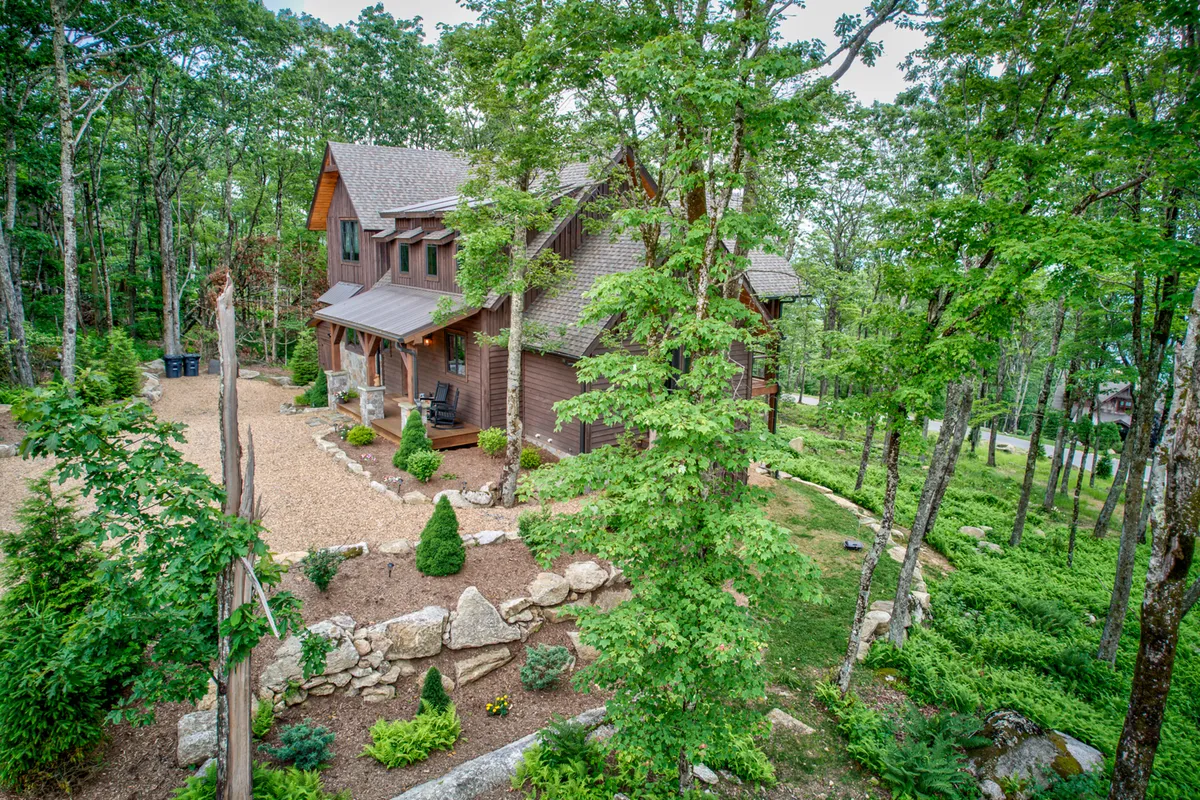 The lodge’s exterior and landscaped garden, with a clear pathway and mature trees, evoke opportunities for outdoor play, nature walks, and gathering around a firepit. The peaceful, welcoming atmosphere invites relaxation and connection.